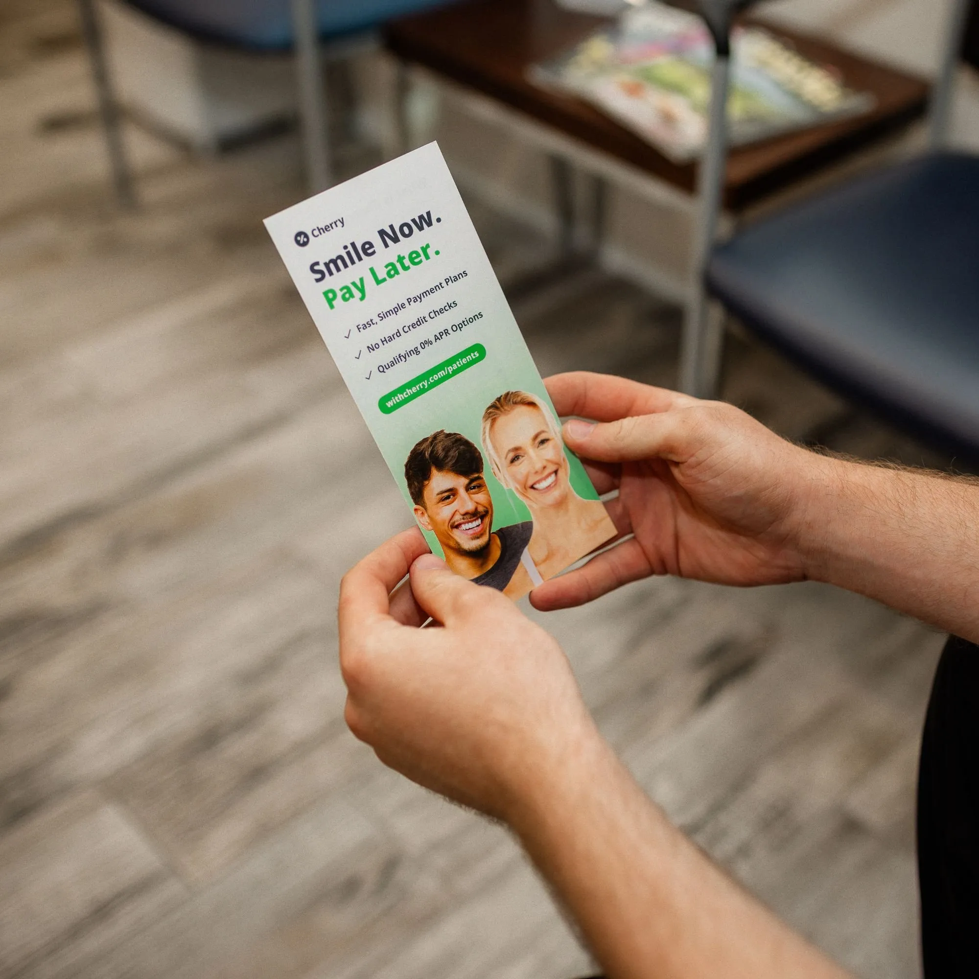 A patient holding a Cherry 'Smile Now. Pay Later.' flyer in the Highland Lakes Dental waiting room