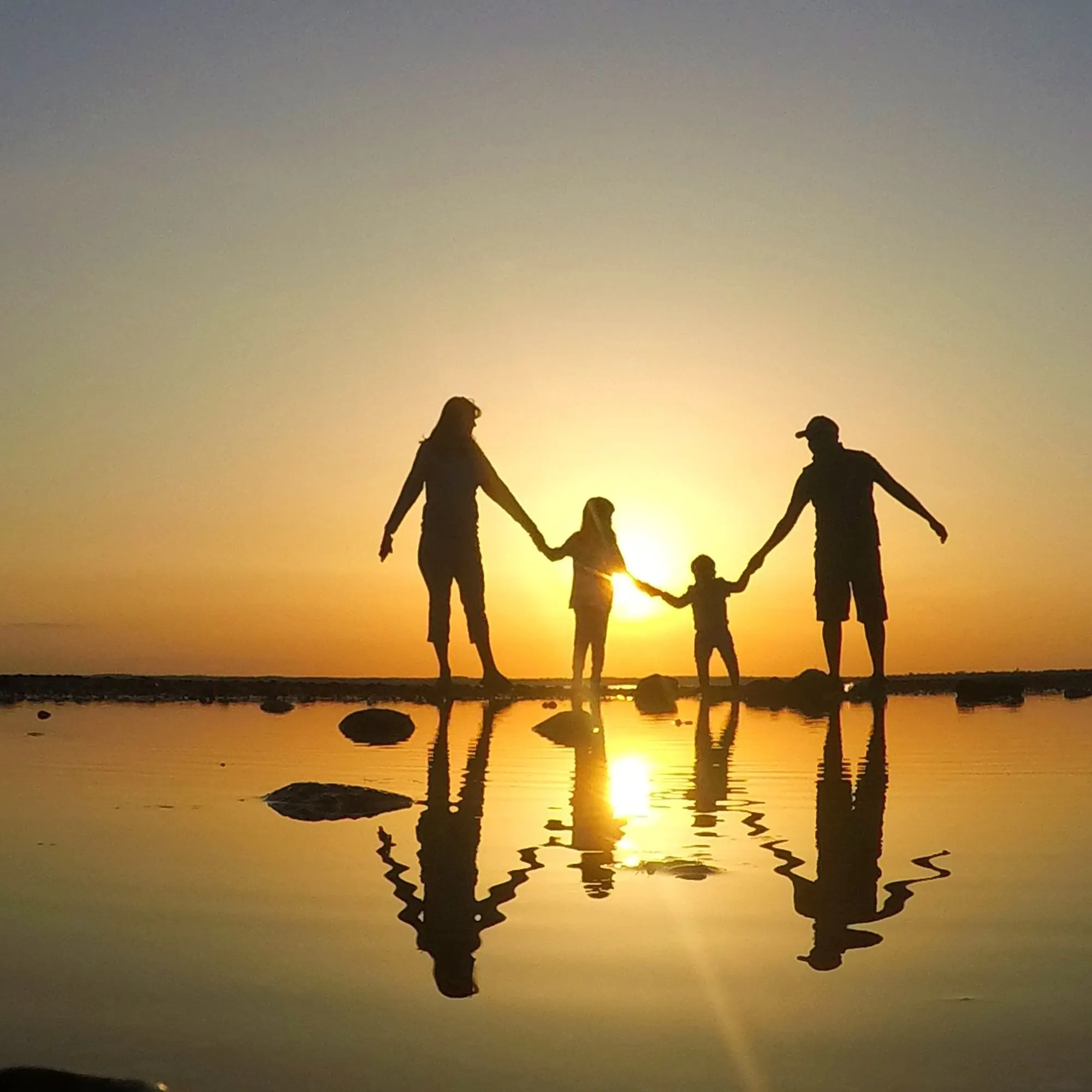 Silhouettes of a family holding hands at sunset