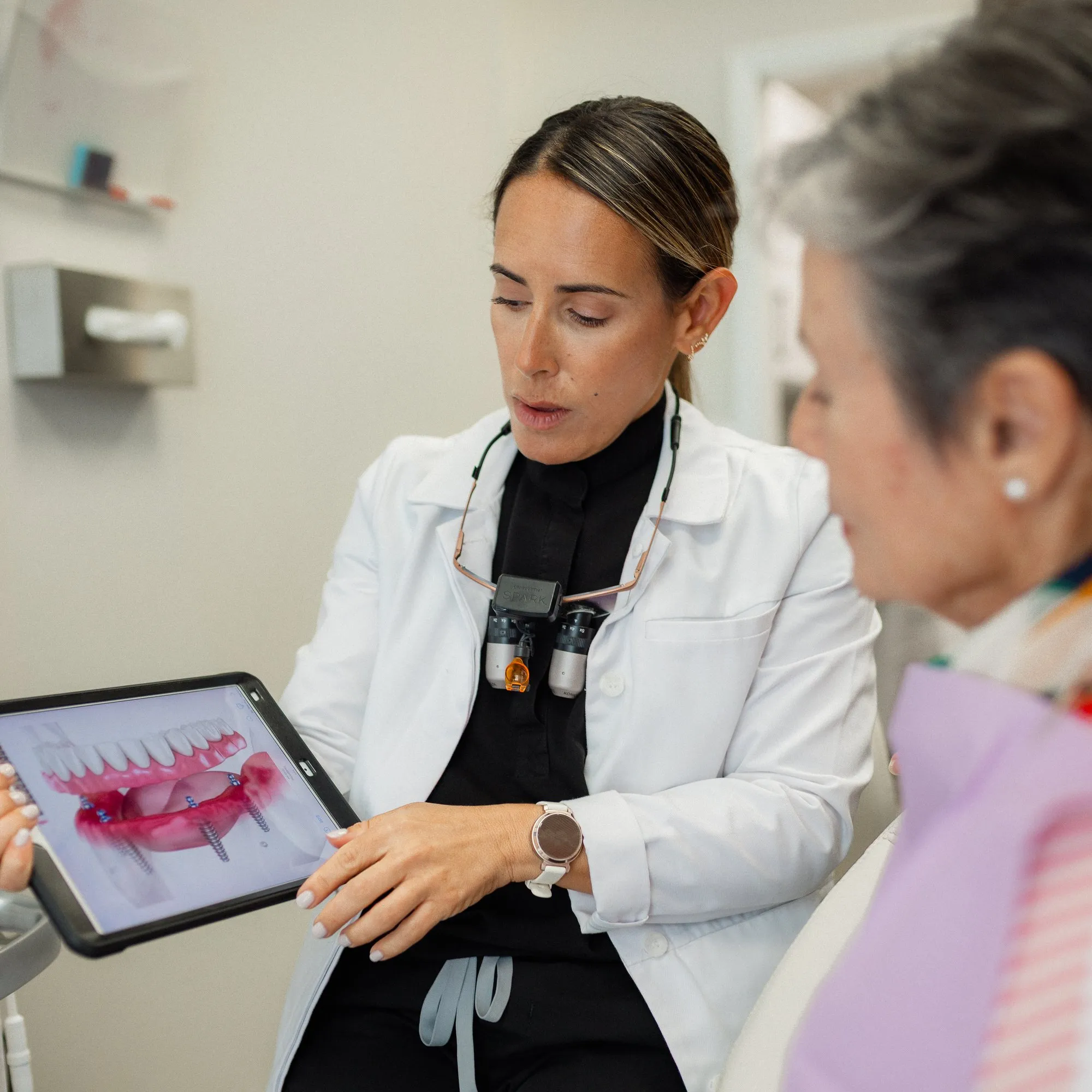 Dentist showing a patient a digital tooth replacement plan on a tablet